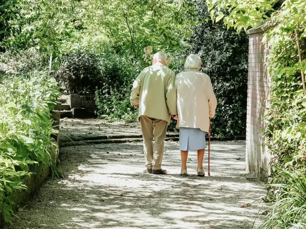 Une personne aînée marche à l'extérieur, accompagnée par une autre personne